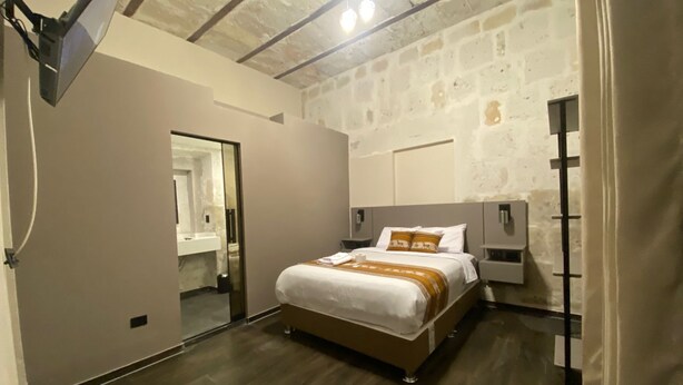 Une chambre à coucher moderne avec un grand lit, une table de chevet, une commode, un miroir et une armoire.