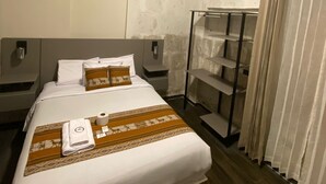 Une chambre à coucher comprenant un lit, des tables de chevet, une armoire et un luminaire au plafond.
