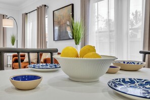 Une table à manger avec un saladier de citrons, une assiette bleue et blanche à motifs et un bol blanc.