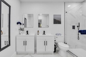 A modern bathroom with two sinks, a toilet, and a shower. - Modern 4BD Retreat- 3 Ensuite BRs - Gated Parking - Walk to Metro (Houston)