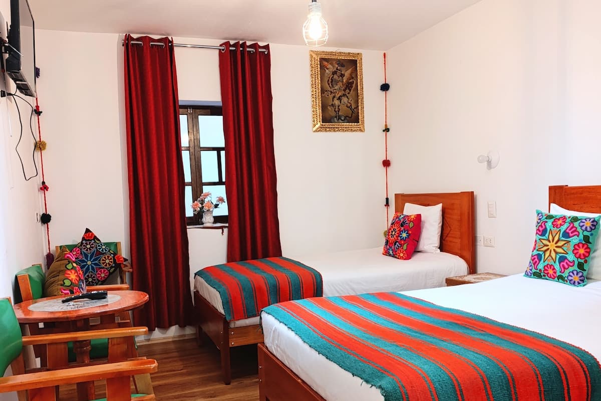 A room with two beds, a small table, and a chair.