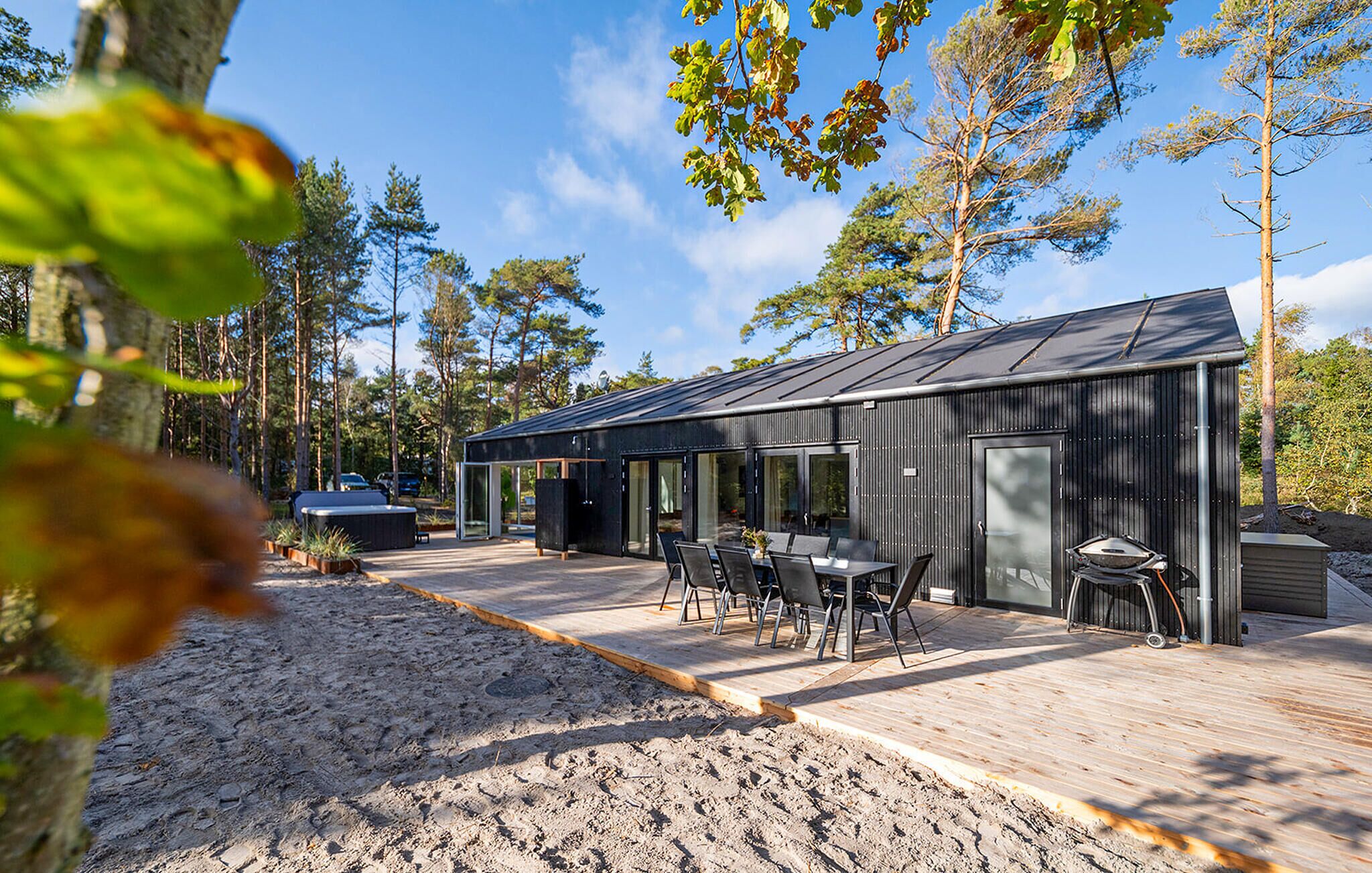 A modern outdoor patio with a dining area, a hot tub, and a barbecue grill.