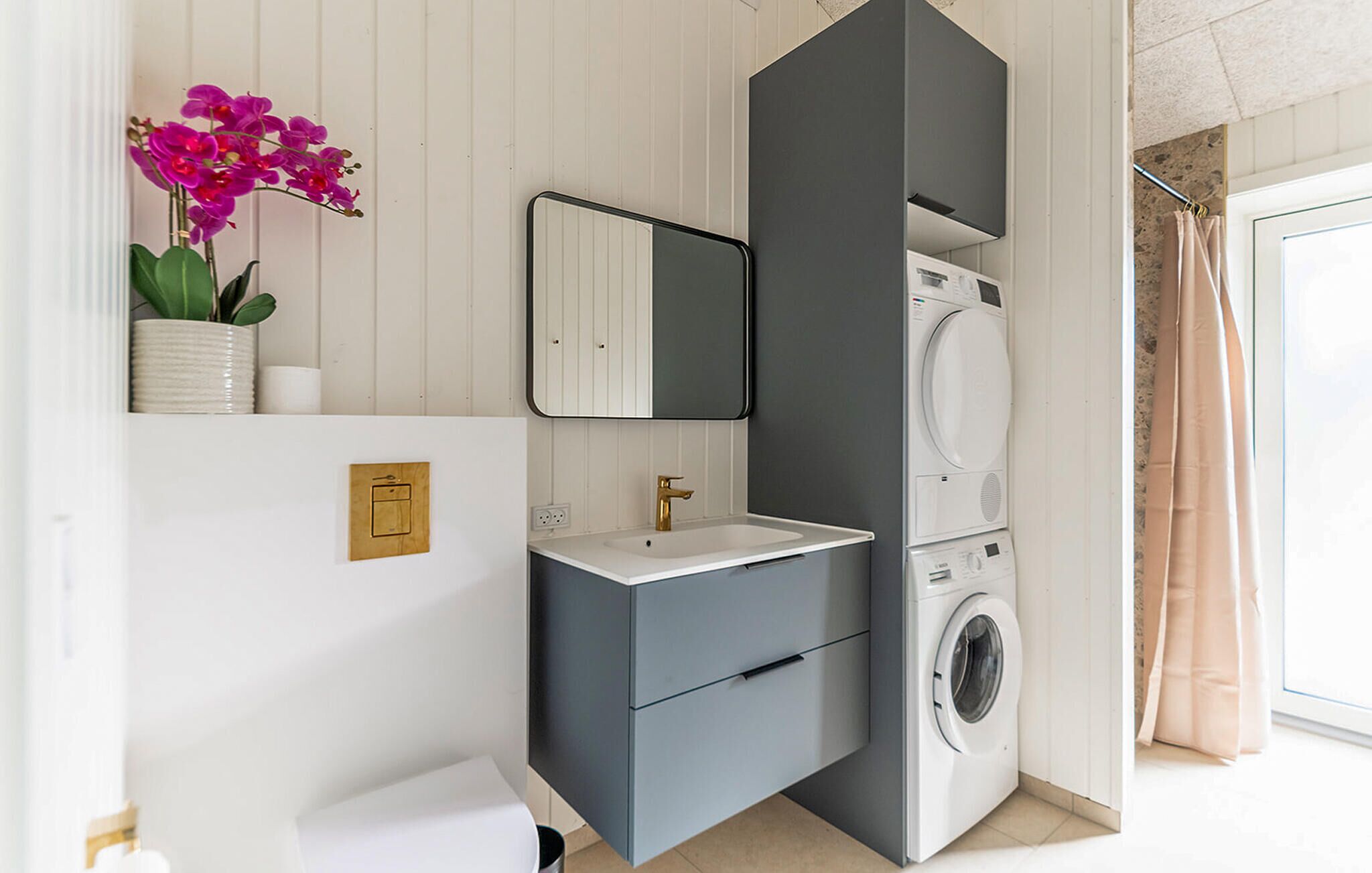 Un baño moderno con lavadora integrada, un lavamanos y un espejo.