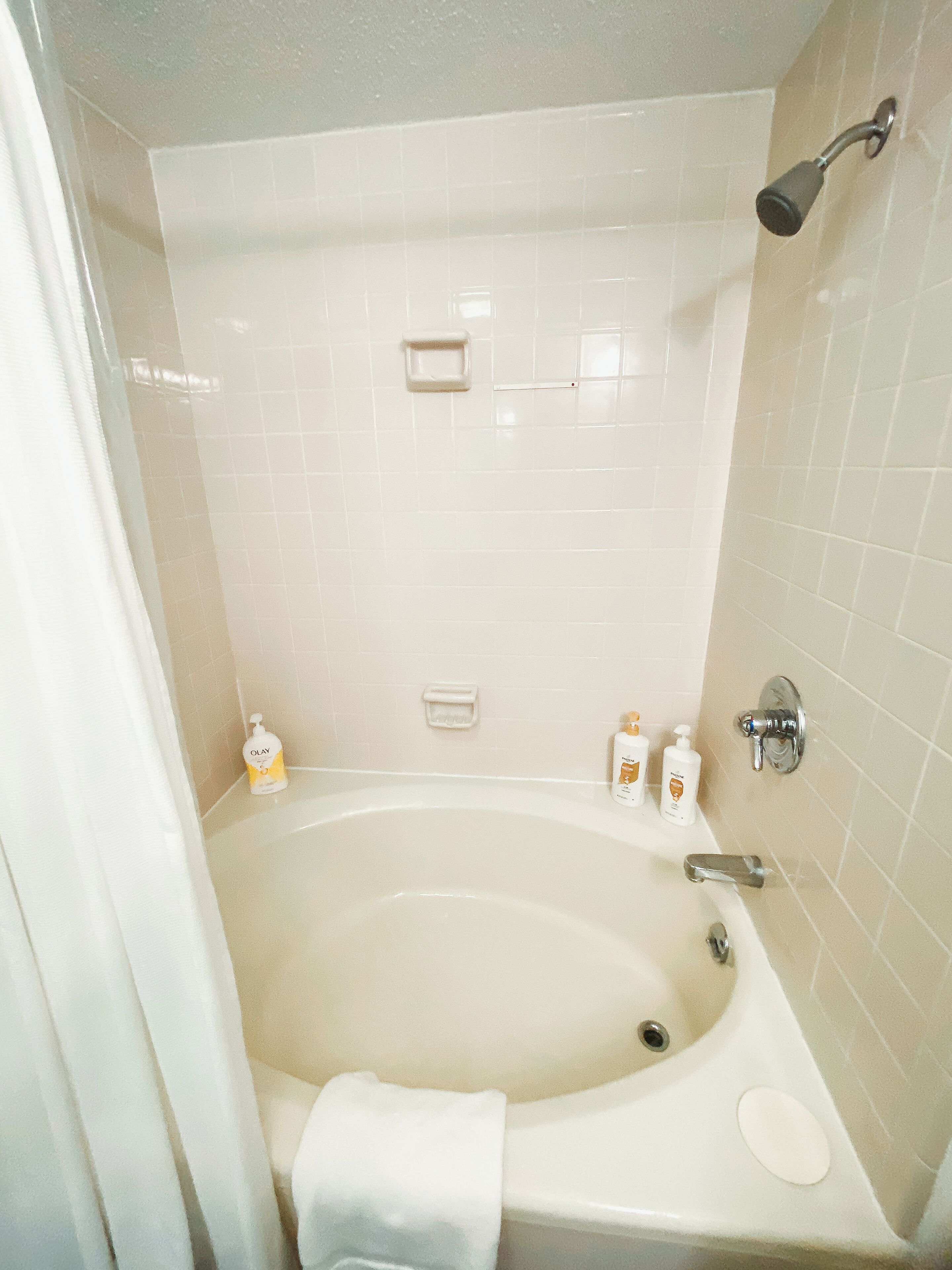 Ein Badezimmer mit einer Badewanne, einer Duschbrause und zwei Seifenspendern an der Wand.