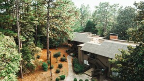 A two-story house with a covered patio and a small garden area. - Three Little Pines Condo 2BD 2BA with Pool Close to Village and Pinehurst Resort (Pinehurst)