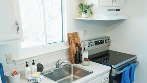 A compact kitchen with white cabinetry, a stainless steel sink, and a built-in oven. - Three Little Pines Condo 2BD 2BA with Pool Close to Village and Pinehurst Resort (Pinehurst)