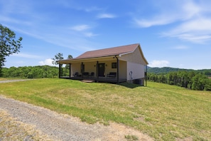 A single-story house with a porch, a gravel driveway, and a grassy lawn.
