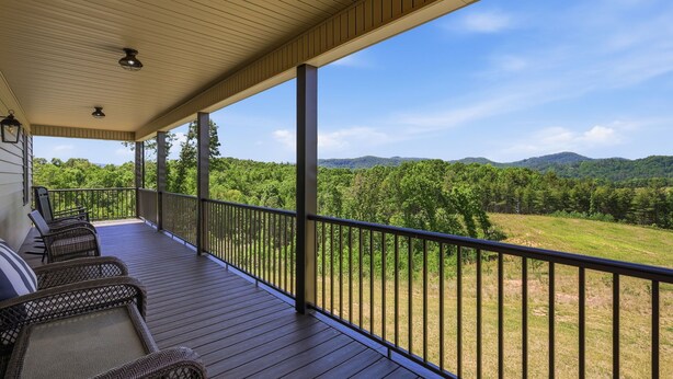 Una terraza techada al aire libre con mobiliario de mimbre y vista a un paisaje boscoso.