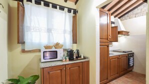 A compact kitchen with wooden cabinets, a microwave, a coffee maker, and a stove. - Amazing home in Todi with swimming pool (Todi)