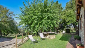 A patio with two lounge chairs, a stone table, and a wooden fence. - Amazing home in Todi with swimming pool (Todi)