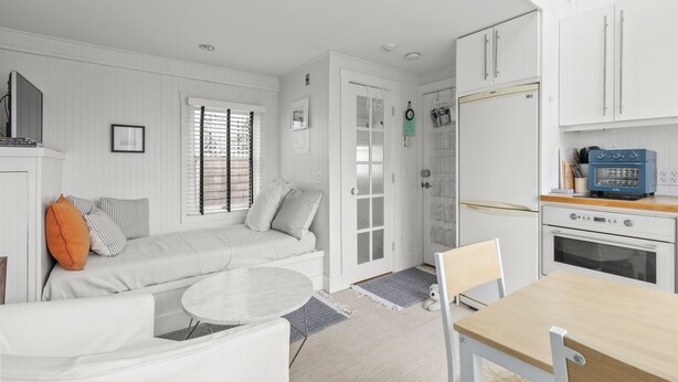 A modern kitchen with white cabinetry, a blue refrigerator, and a dining area with a round table and chairs.