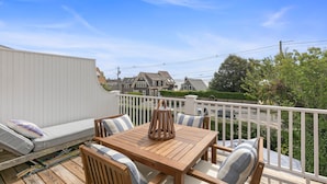 A wooden deck with a white railing, a sofa, and a table with chairs.