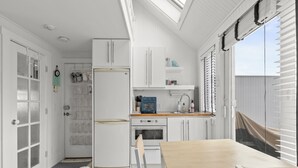 A compact kitchen with white cabinetry, a wooden table, and a dog bed.