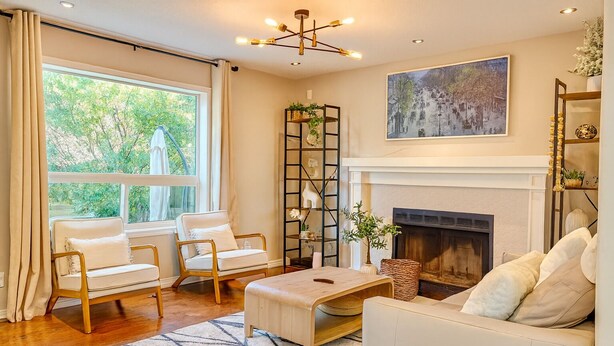 A living room with a fireplace, two white sofas, a coffee table, and a bookshelf. - Blue-bell Cottage w/Garage, Fireplace & Backyard (Calgary)