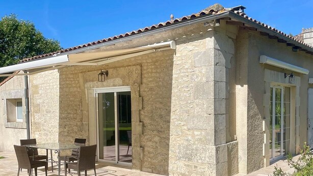 Un edificio de piedra con un patio empedrado, una puerta de cristal y una pequeña mesa con sillas.
