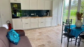 Una cocina moderna con armarios blancos, encimera de madera y vistas al exterior a través de amplios ventanales.