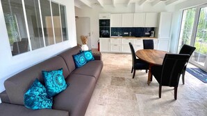 Una cocina moderna con armarios blancos y un comedor con una mesa y sillas de madera.