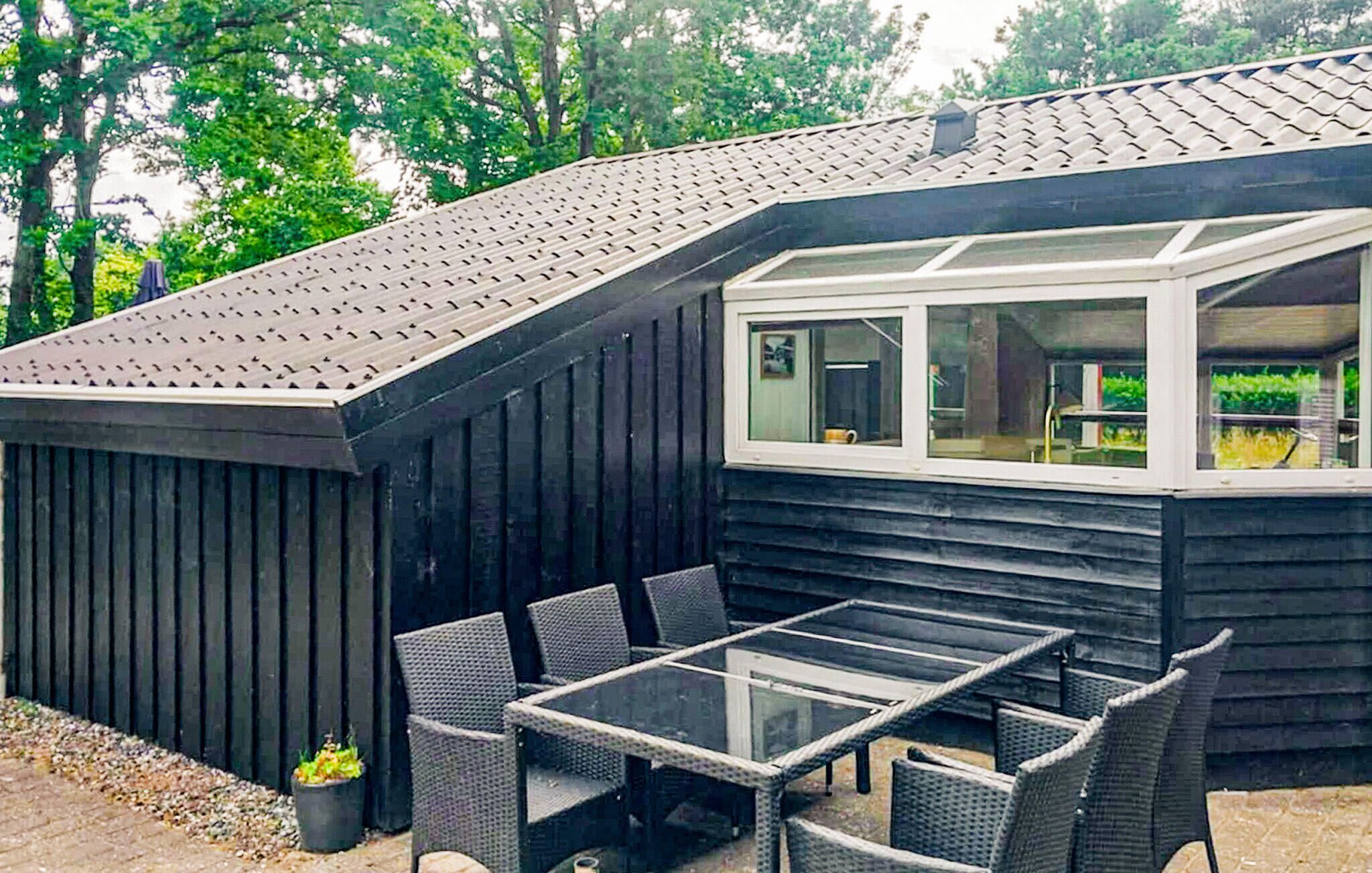 A black wooden building with a sloped roof and a glass window.