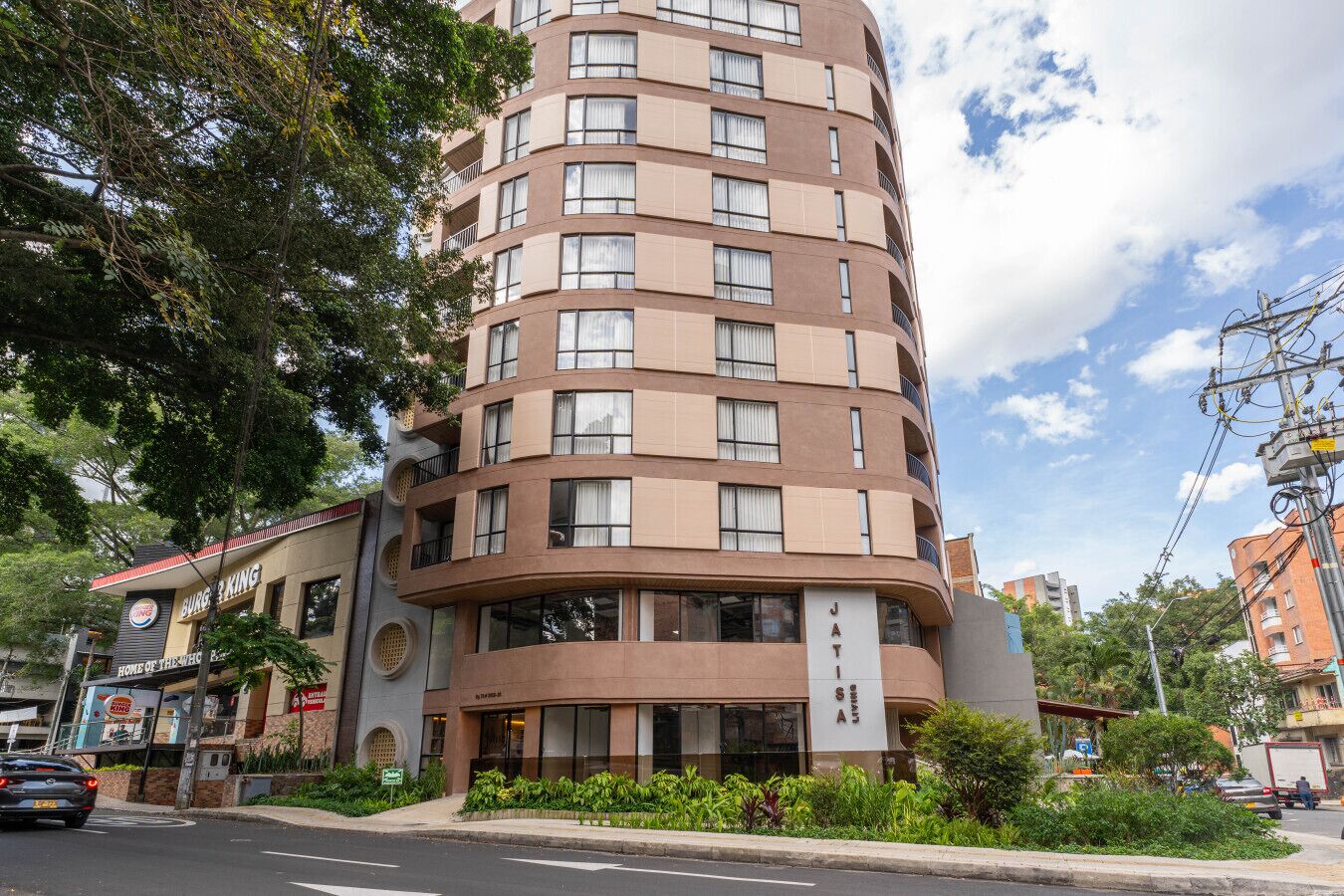 A multi-story hotel with a curved facade, large windows, and a sign indicating it is a JATIS hotel.