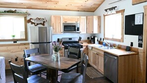 A kitchen with wooden cabinets, a stainless steel refrigerator, a microwave, a stove, and a sink. - Cozy Riverfront Fish Cabin (Paris)