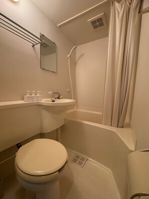 Un baño pequeño con inodoro, lavamanos y ducha.