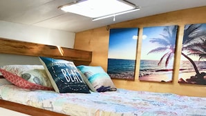 A cabin with a bed, a headboard, a control panel, and wall-mounted artwork.