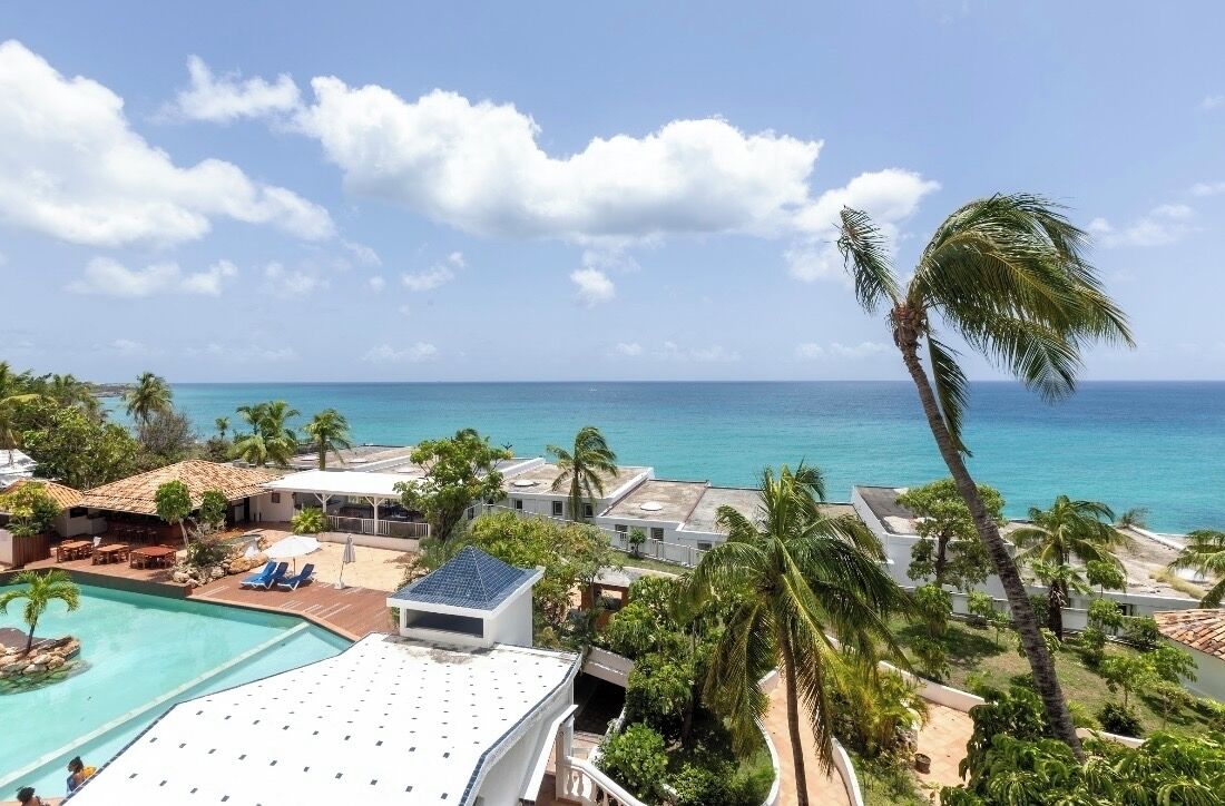A resort with a pool, beach chairs, and palm trees.