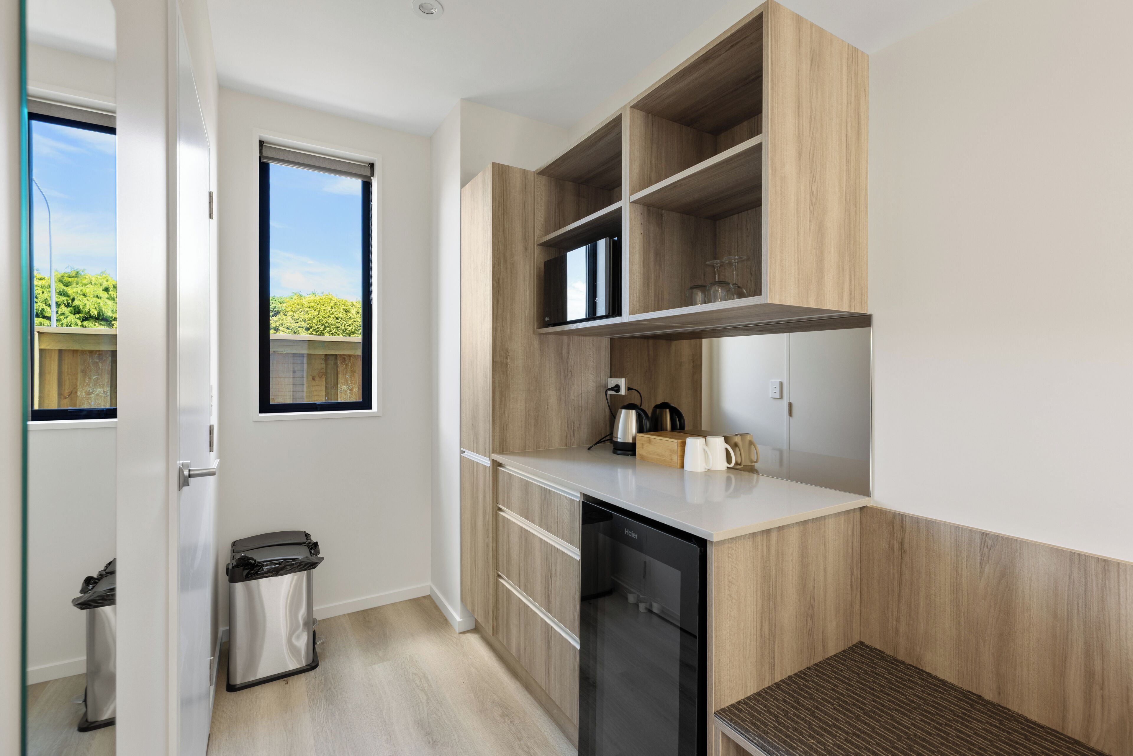 Eine moderne Küche mit Holzschränken, einem Geschirrspüler und einem Fenster mit Blick ins Grüne.