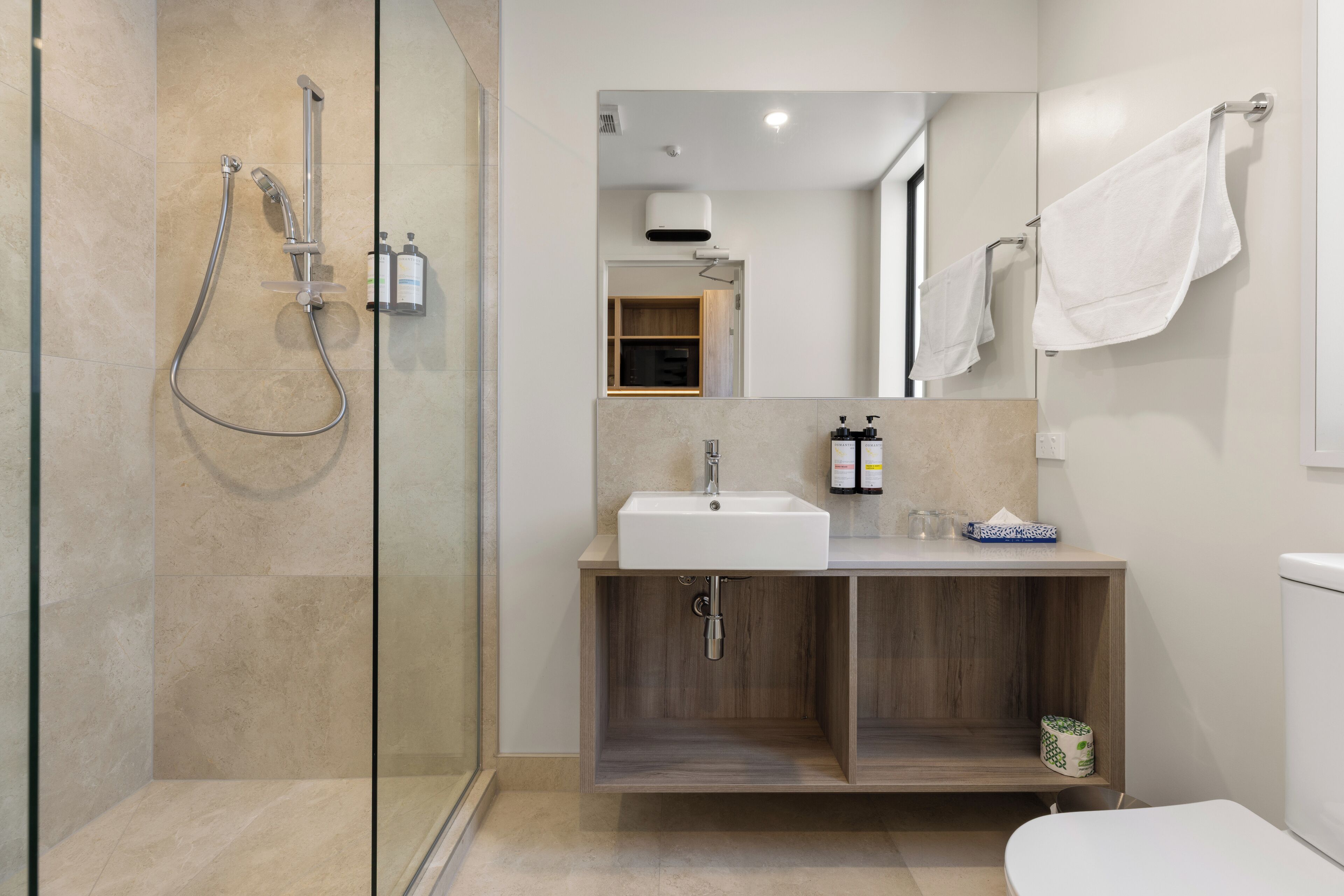 Une salle de bain moderne avec une douche à parois de verre, un meuble-lavabo en bois et des toilettes.