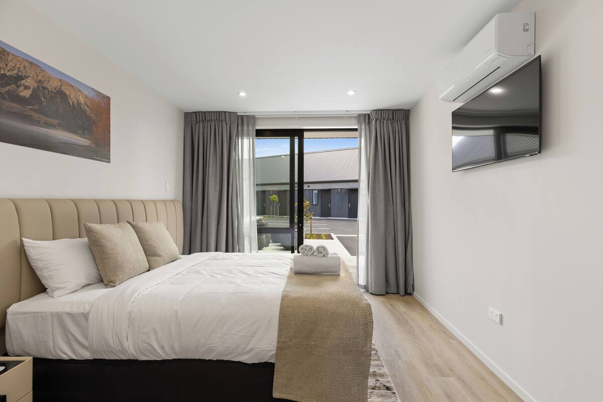 Un dormitorio moderno con cama, televisión de pantalla plana, aire acondicionado y vistas al exterior.