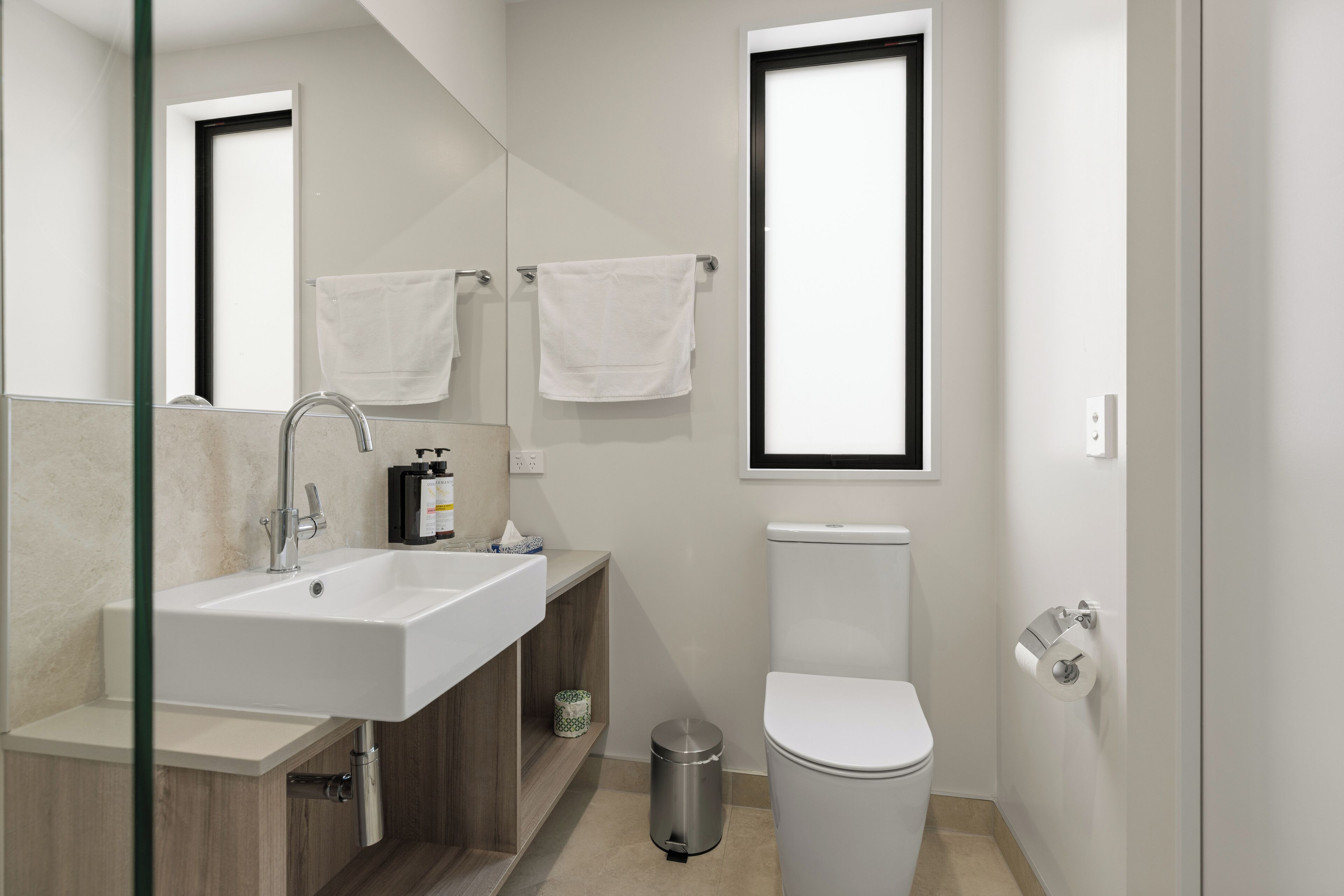 A modern bathroom with a sink, mirror, and toilet.