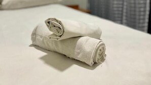 Una cama bien tendida con una toalla enrollada en una habitación de hotel.