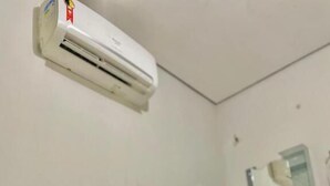 Una habitación de hotel con una cama, una toalla enrollada y un equipo de aire acondicionado fijado en la pared.