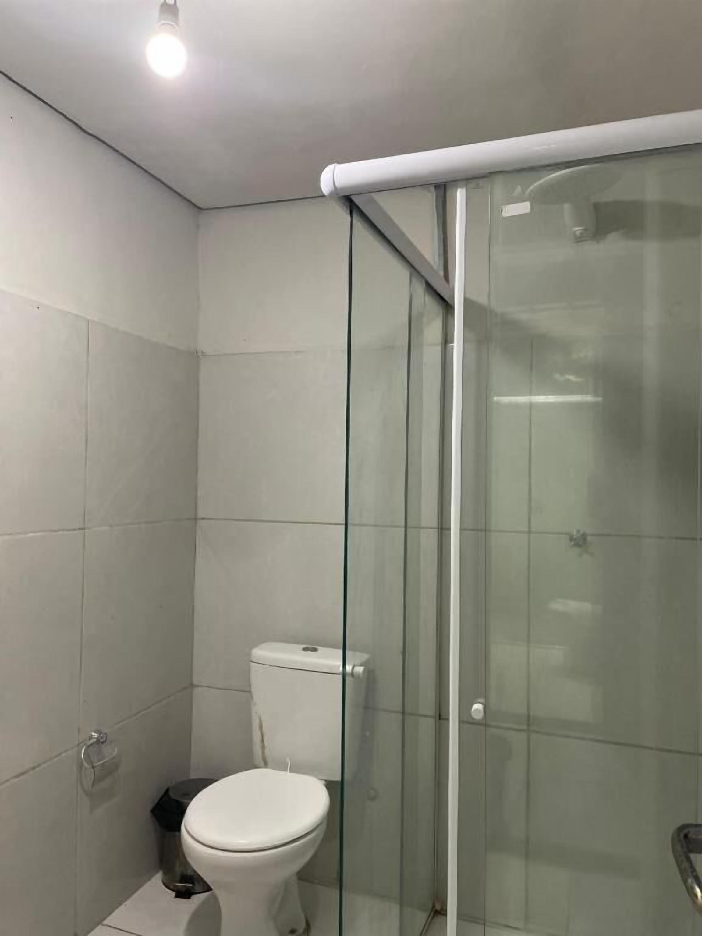 A bathroom with a glass-enclosed shower, a white toilet, and tiled walls.
