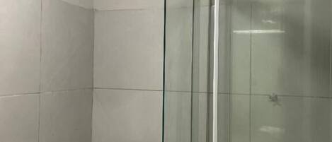 A bathroom with a glass-enclosed shower, a white toilet, and tiled walls.