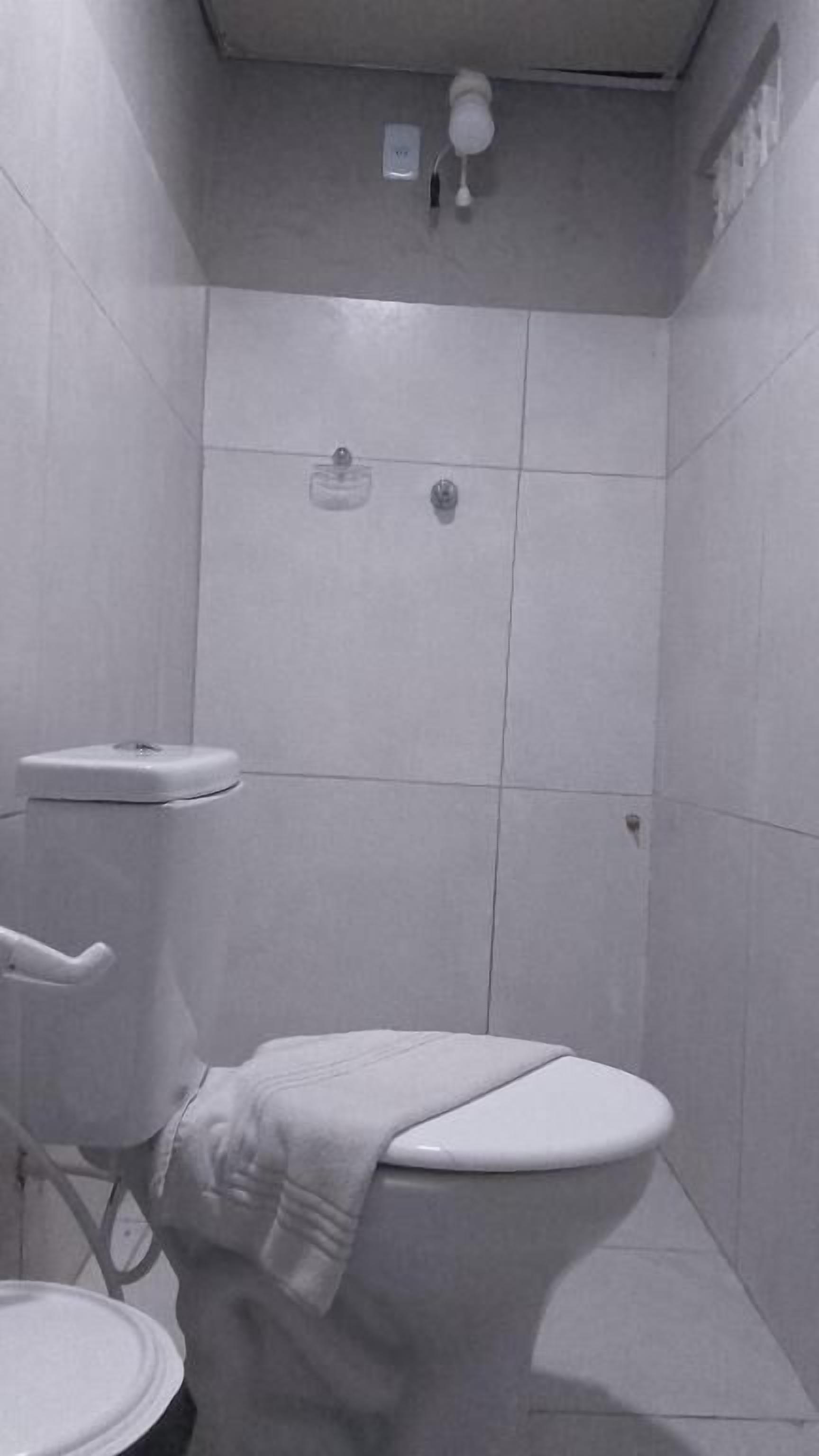 Un baño pequeño y cerrado con inodoro, lavabo y zona de ducha.