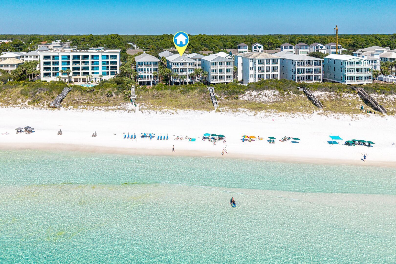 A coastal hotel with multiple buildings, a sandy beach, and clear turquoise waters.