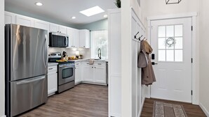 Una cocina moderna con armarios blancos, electrodomésticos de acero inoxidable y suelo de madera.
