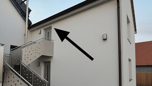 A building with a staircase and a large black arrow pointing to the right. - Modern & cozy apartment opposite the Deister (Barsinghausen)