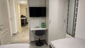 A hotel room with two beds, a TV, a mirror, and a small desk with a chair. - Modern & cozy apartment opposite the Deister (Barsinghausen)