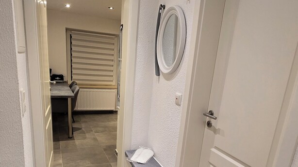 A hallway with a bathroom, a dining area, and a door. - Modern & cozy apartment opposite the Deister (Barsinghausen)