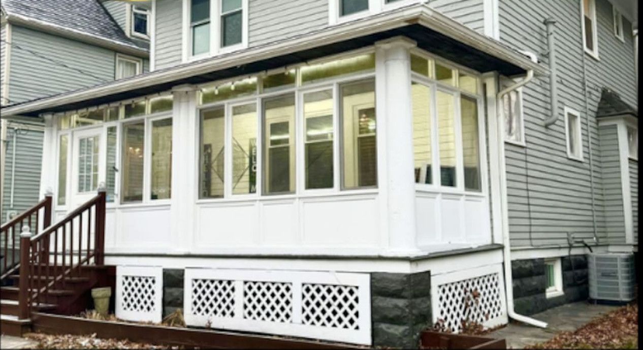 A two-story house with a covered porch and a staircase leading to the entrance.