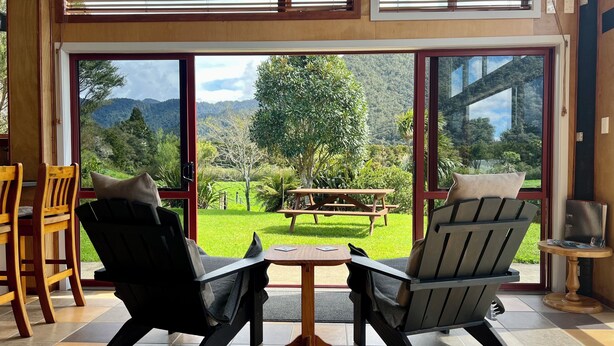 Una habitación con dos sillas frente a un ventanal que ofrece vistas a un área verde y árboles.