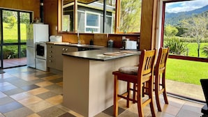 Una cocina moderna con una isla grande, armarios de madera y vistas a un paisaje exuberante.