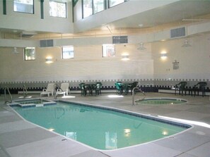 Una piscina coperta con diverse corsie, circondata da sedie e tavoli.