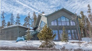 A modern building with large windows and a sloped roof, surrounded by snow and trees. - Peaks & Peace - Spacious Condo in Silverthorne with jacuzzi and fitness room (Silverthorne)