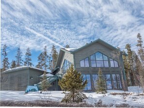 Un edificio moderno con ampie finestre e un tetto spiovente, circondato da neve e alberi.