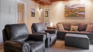 A living room with two black leather sofas, a brown sofa, and a matching ottoman. - Peaks & Peace - Spacious Condo in Silverthorne with jacuzzi and fitness room (Silverthorne)