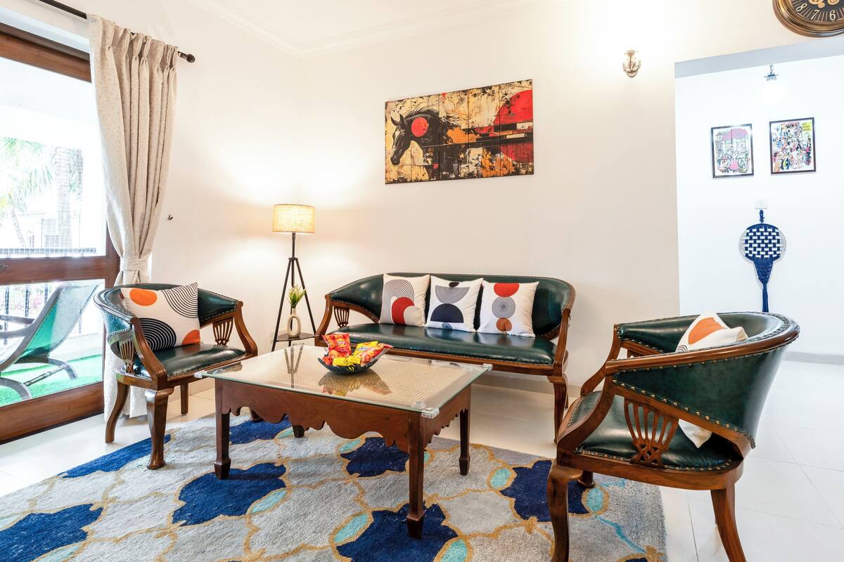 A living room with a sofa, two armchairs, a coffee table, and a patterned rug.