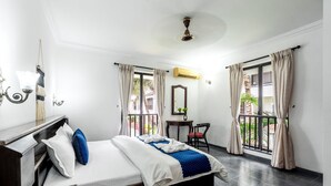 Une chambre d’hôtel avec un lit, un bureau, une chaise et un balcon avec des rideaux.